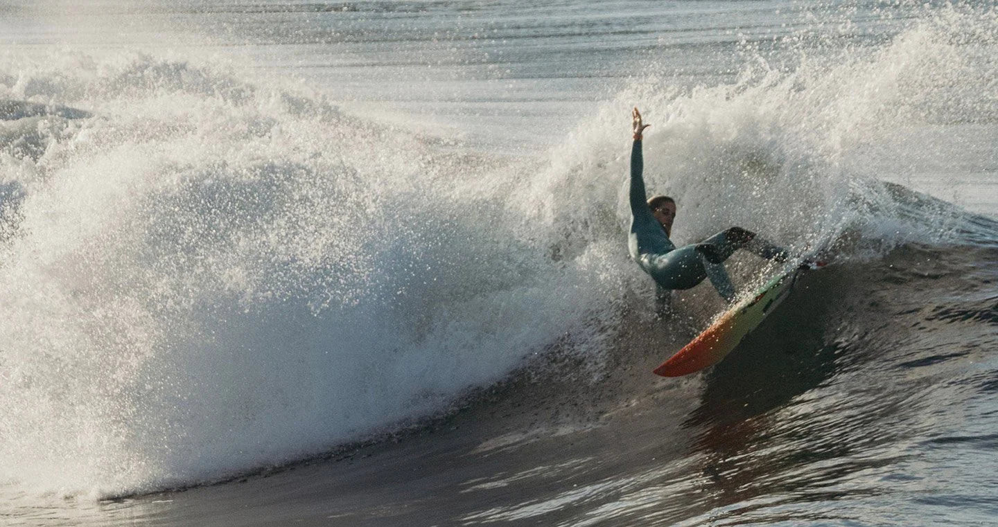 Surfer carving through a powerful wave, showcasing skill and precision.