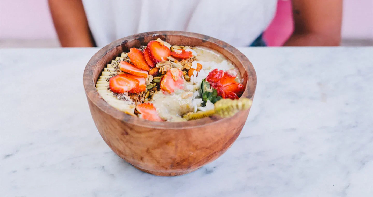 Delicious smoothie bowl topped with fresh strawberries, granola, and coconut.