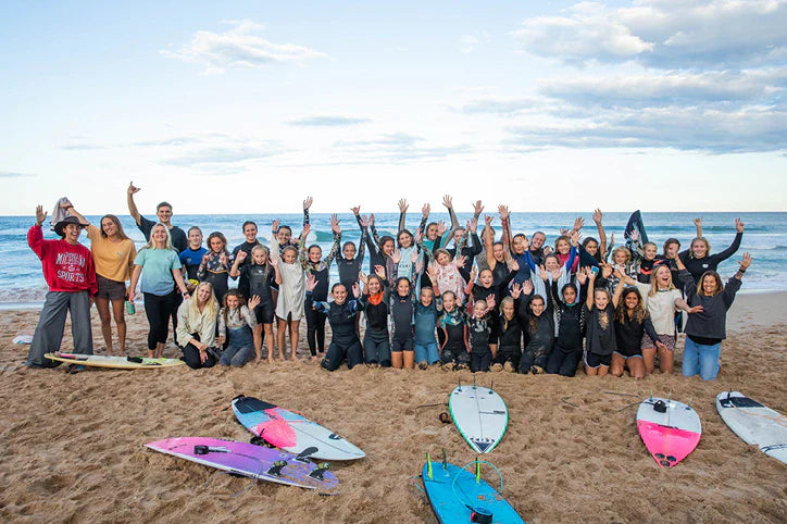 Group of surfers celebrating on the beach at the Her Wave Teams Classic presented by Sisstrevolution.