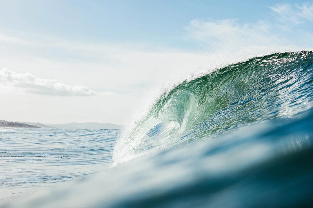 Crystal-clear ocean wave curling under a bright blue sky.